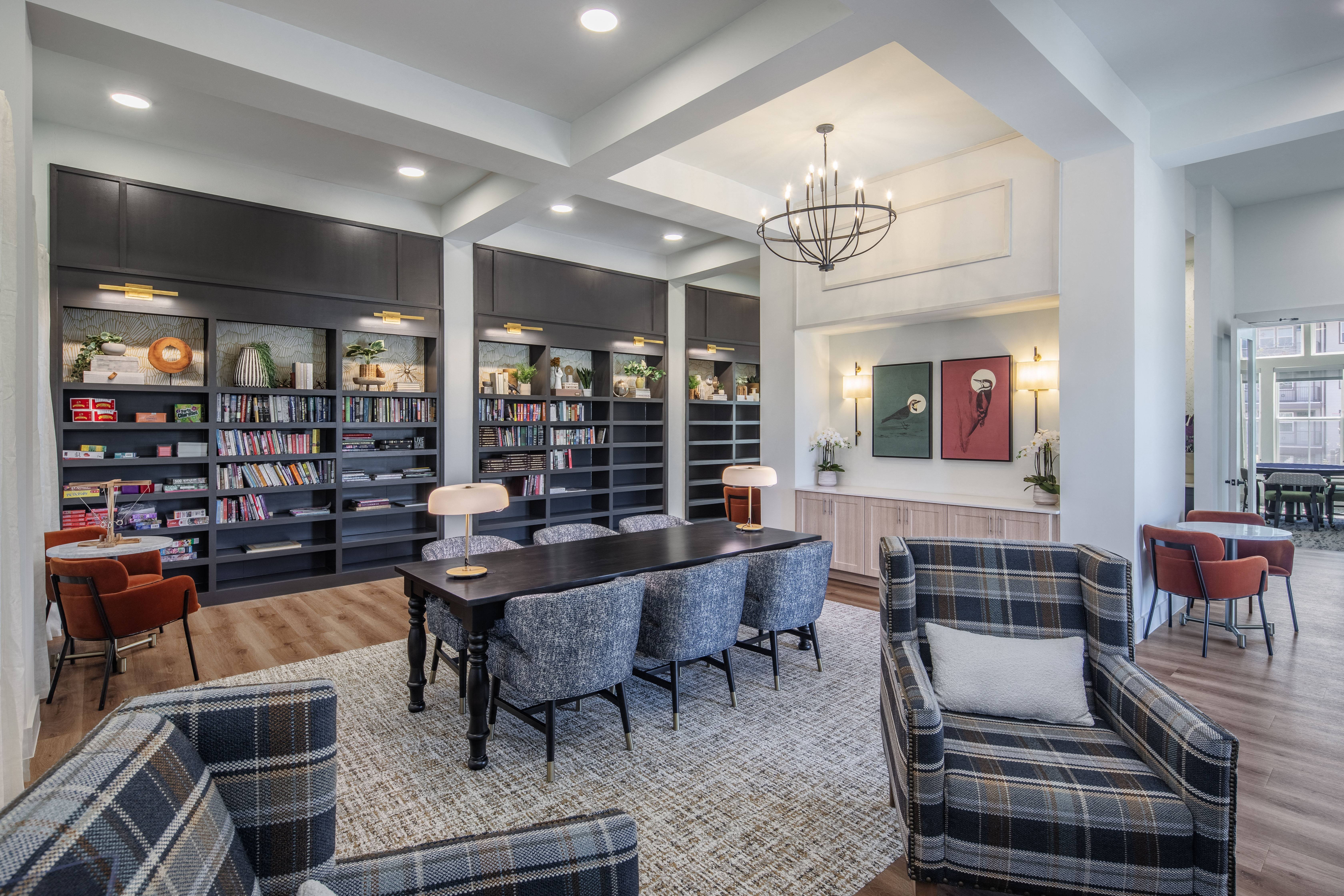 a library with sitting areas and a chandelier at a senior apartment community